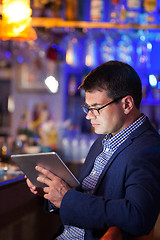 Image showing Businessman reading a tablet in a cocktail bar