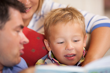 Image showing Cute little boy reading a book with his parents