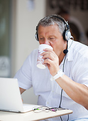 Image showing Man Drinking Coffee and Using Laptop at Cafe