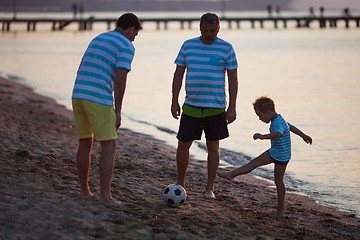 Image showing Grandfather, Father and Son Kicking Ball on Beach