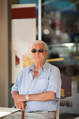 Image showing Elderly man waiting at a table outside a store