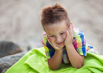 Image showing Boy with Head in Hands on Green Beach Blanket