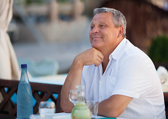 Image showing Smiling pensive middle-aged man at a restaurant