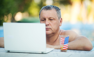 Image showing Man in Swimming Pool with Laptop and Beverage