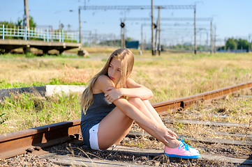 Image showing Sad young girl sitting lonely on rail track