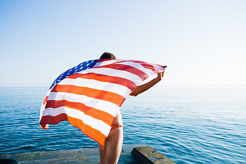 Image showing Back view of female with American flag against  sea