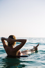 Image showing Back view of relaxing woman floating on inflatable ring