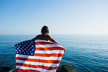 Image showing Back view of female with American flag against  sea