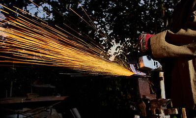 Image showing Worker cutting metal with grinder. Sparks while grinding iron