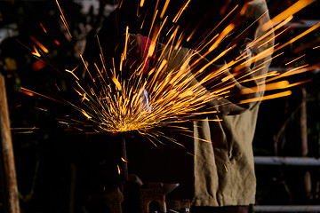 Image showing Worker cutting metal with grinder. Sparks while grinding iron