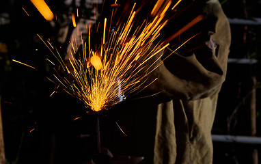 Image showing Worker cutting metal with grinder. Sparks while grinding iron