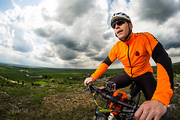 Image showing Young man cycling on a rural road through green meadow