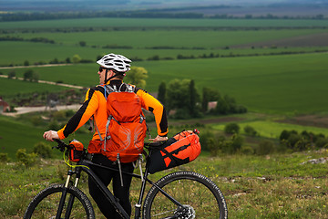 Image showing Young man cycling on a rural road through green meadow