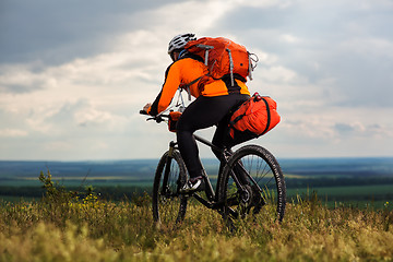 Image showing Young man cycling on a rural road through green meadow