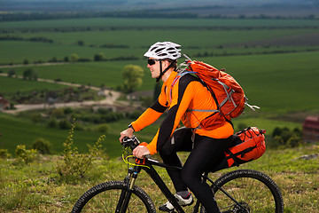 Image showing Young man cycling on a rural road through green meadow