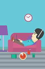 Image showing Man lying on sofa with many gadgets.