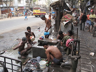 Image showing Streets of Kolkata. Indian people wash themselves on a street