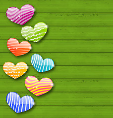 Image showing Multicolored striped hearts on green wooden texture for Valentin