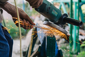 Image showing Close-up of workman working with iron