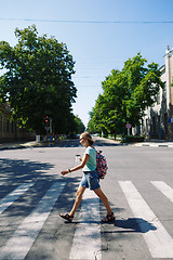 Image showing young woman with backpack and coffee crossing the street