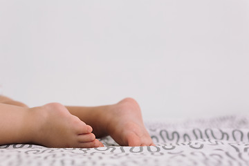 Image showing Barefoot baby on bedspread