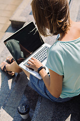 Image showing Young short-haired girl working on laptop in sunlight