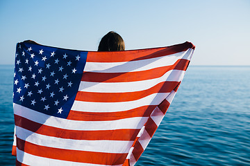 Image showing Back view of female with American flag against  sea