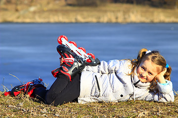 Image showing young girl in roller skates lays on the ground