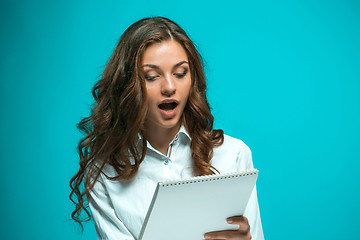 Image showing Surprised young business woman with tablet for notes on blue background