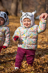 Image showing The two little baby girls standing in autumn leaves