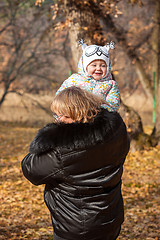 Image showing The little baby girl and grandmother standing in autumn leaves