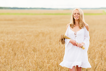 Image showing happy young woman with spikelets on cereal field