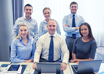 Image showing smiling business people with laptop in office