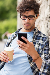 Image showing man with smartphone drinking coffee on city street