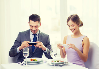 Image showing smiling couple with appetizers and smartphones