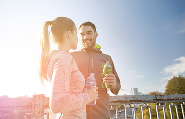 Image showing smiling couple with bottles of water outdoors