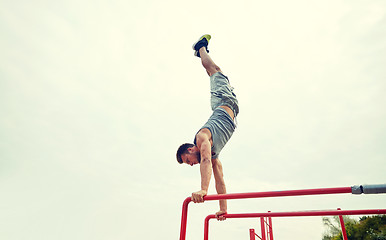 Image showing young man exercising on parallel bars outdoors