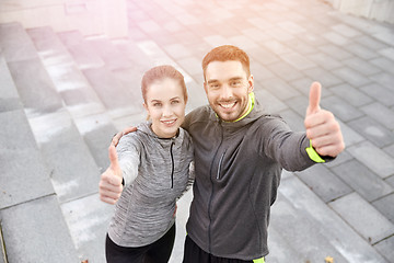 Image showing smiling couple showing thumbs up on city street