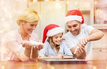 Image showing happy family in santa helper hats making cookies