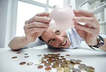 Image showing businessman with piggy bank and coins at office