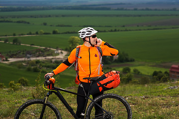 Image showing Young man standing near the cycle on a green meadow