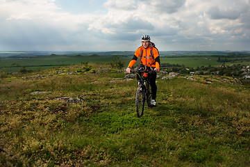 Image showing Young man cycling on a rural road through green meadow