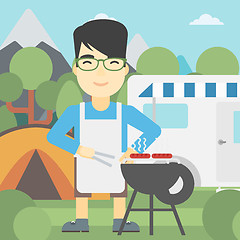 Image showing Man having barbecue in front of camper van.