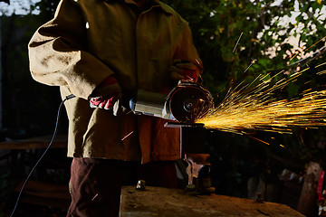 Image showing Worker cutting metal with grinder. Sparks while grinding iron