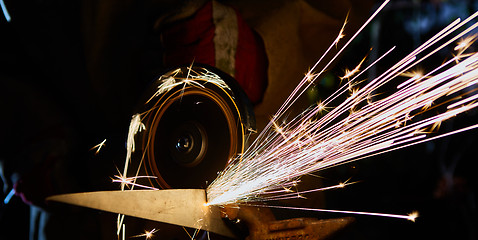 Image showing Worker cutting metal with grinder. Sparks while grinding iron