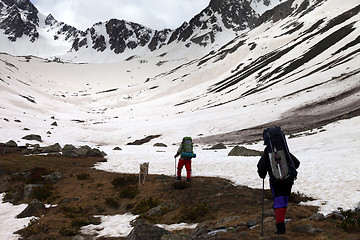 Image showing Two hikers with dog at spring snow mountain in morning