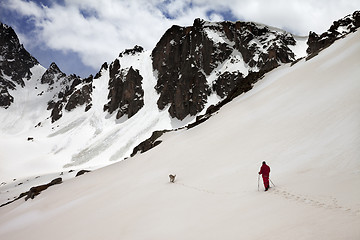 Image showing Hiker with dog in snow mountain at spring morning