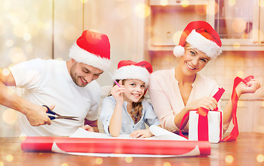 Image showing smiling family in santa helper hats with gift box