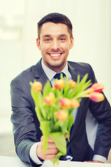 Image showing smiling handsome man giving bouquet of flowers