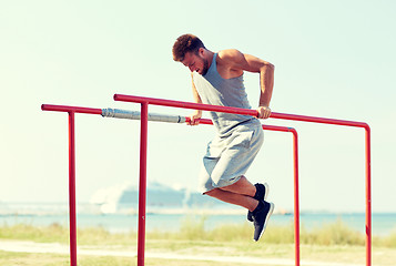 Image showing young man exercising on parallel bars outdoors